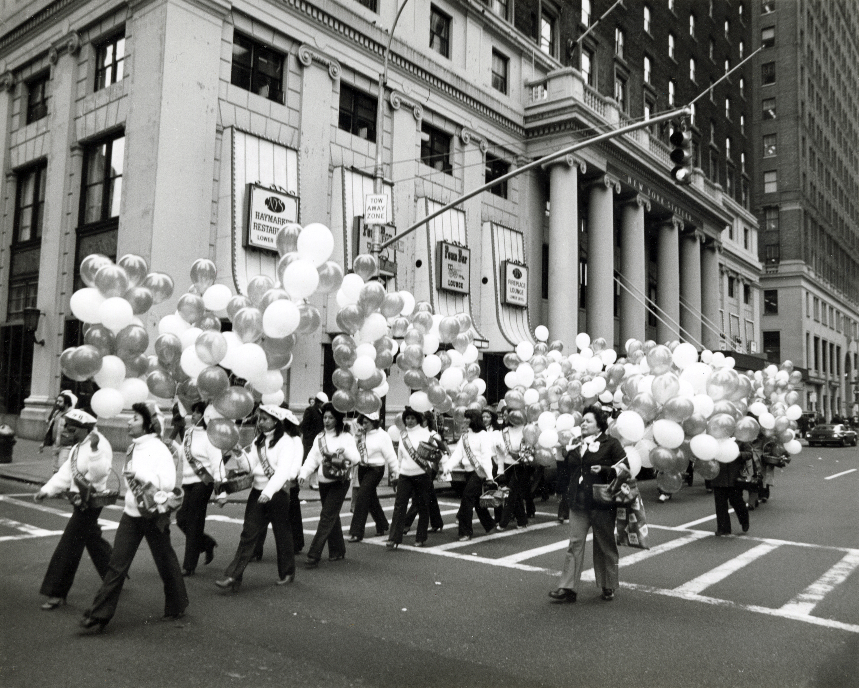 Kathy Andrade marching in front of a large group of union women carrying bunches of balloons during a 1976 rally for President Jimmy Carter.